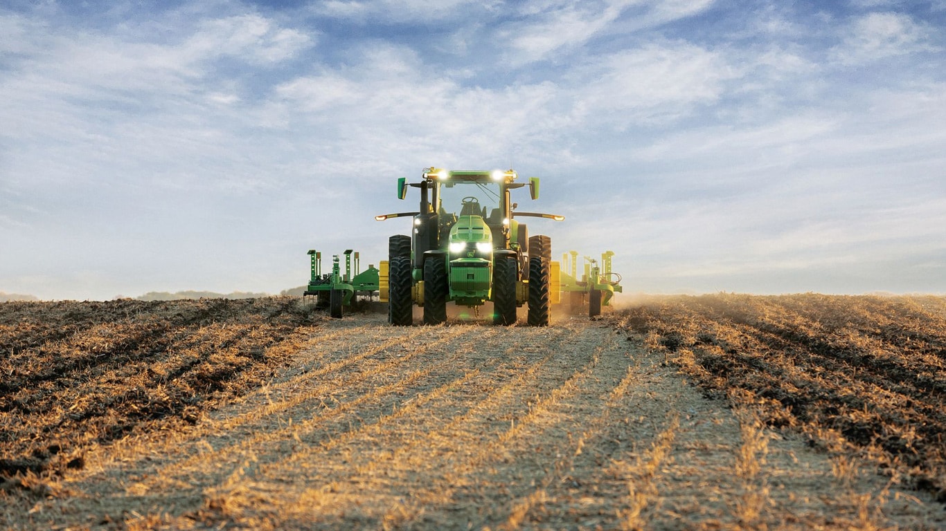Samohybný traktor John Deere ťahajúci zariadenie na orbu na otvorenom poli.