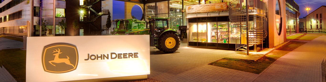 Čelný pohľad na budovu ústredia John Deere s jazierkom a vŕbami v popredí