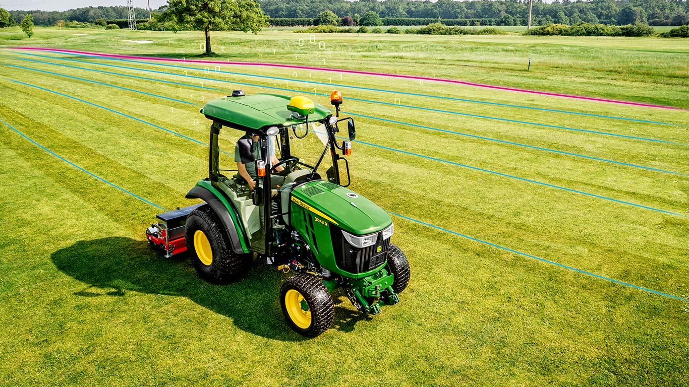 Správca golfového ihriska pracuje v oblasti trávnika s kompaktným úžitkovým traktorom John Deere.