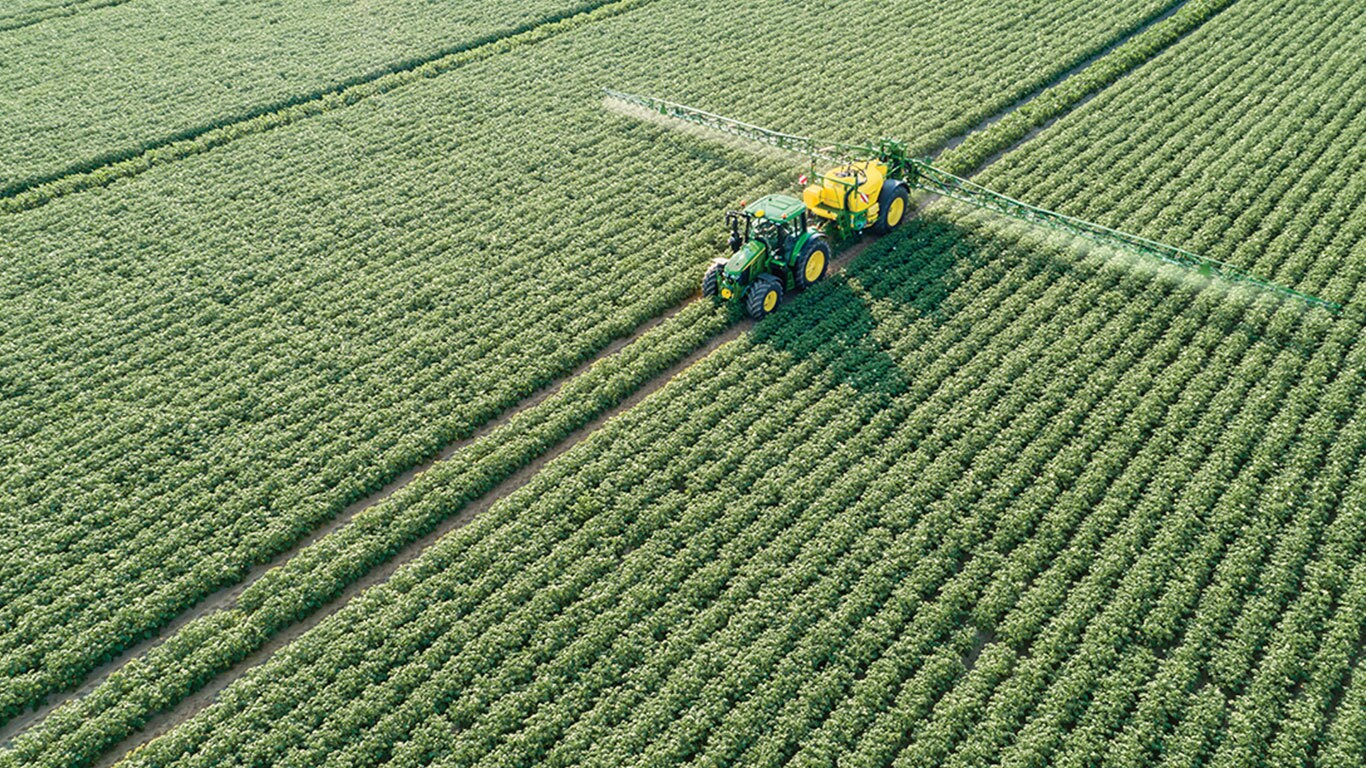 Traktor John Deere radu 6M ťahaj&uacute;ci vlečn&yacute; postrekovač M700 v zemiakovom poli