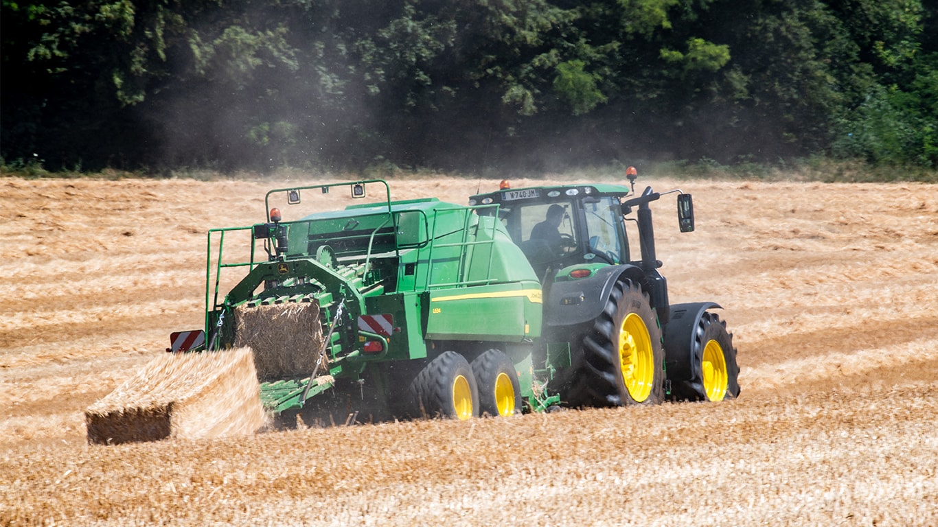 Veľký štvorcový lis John Deere L634 s traktorom 6R v slame