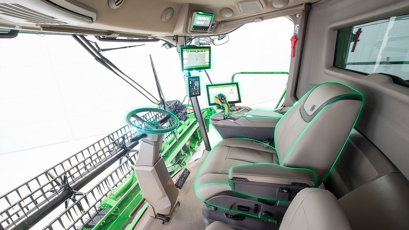 Interiér kabíny kombajnu s displejmi precízneho poľnohospodárstva, volantom a žacím valom viditeľným cez čelné sklo