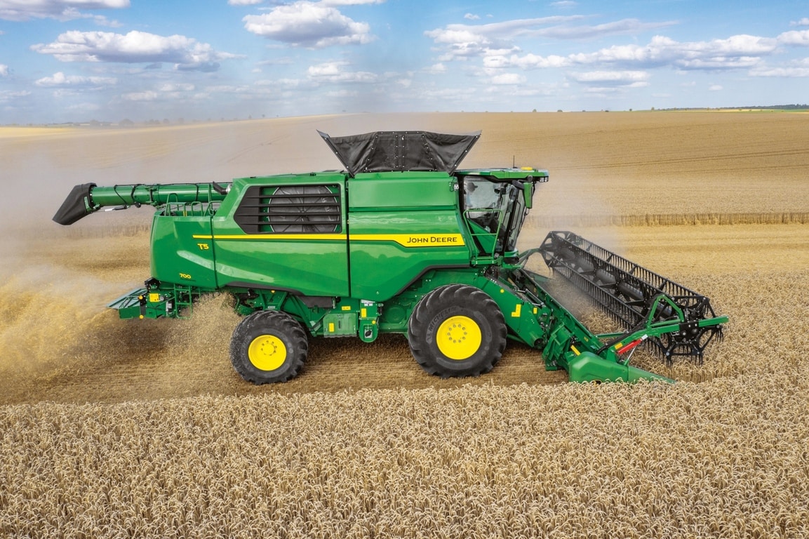 Bočný pohľad na kombajn John Deere so žacím valom na zber pšenice na rozľahlom poľnohospodárskom poli