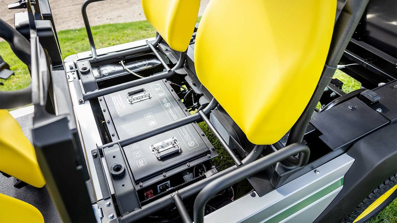Detailný pohľad na dve lítiové batérie nainštalované pod jasne žltými sedadlami v elektrickom úžitkovom vozidle John Deere Gator GS.