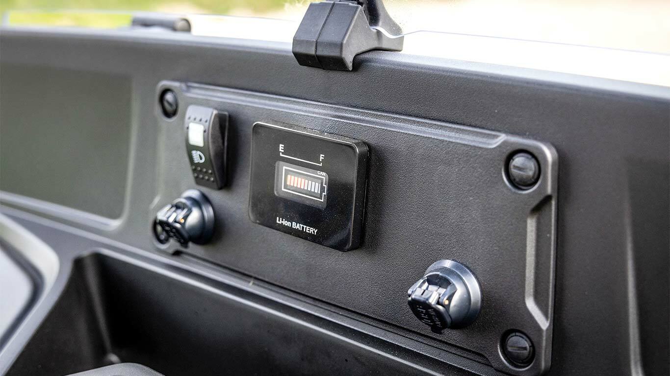 Palubná doska elektrického modelu vozidla John Deere Gator GS zobrazujúca ukazovateľ stavu batérie a napájacie porty.