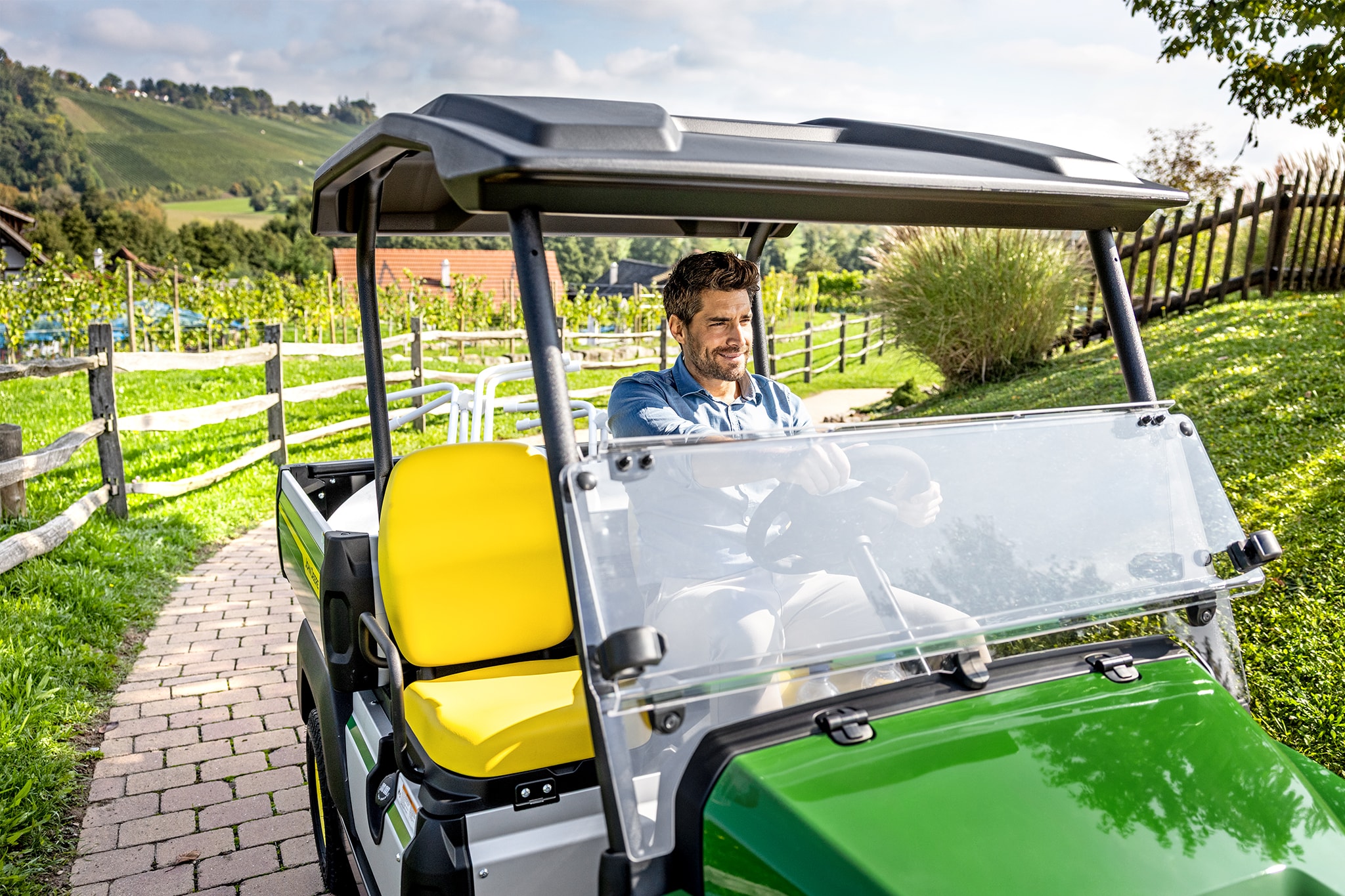 Detailný pohľad na interiér vozidla John Deere Gator GS so žltými sedadlami a volantom Detailný pohľad na interiér vozidla John Deere Gator GS so žltými sedadlami a volantom