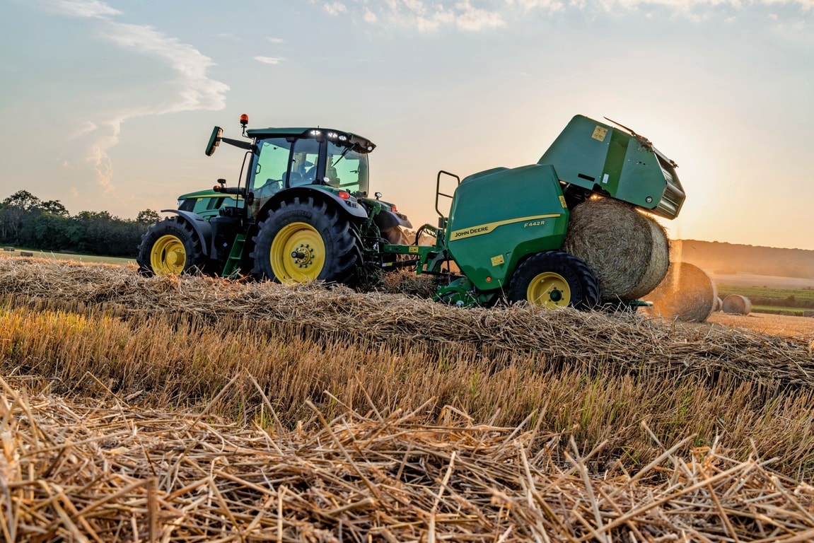 Lis na balíky John Deere F442M ťahaný traktorom John Deere 6M, ktorý vyhadzuje balíky slamy