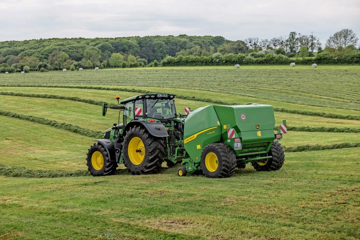 John Deere F442R lis na balíky ťahaný traktorom John Deere 6M na kopcovitom trávnatom poli