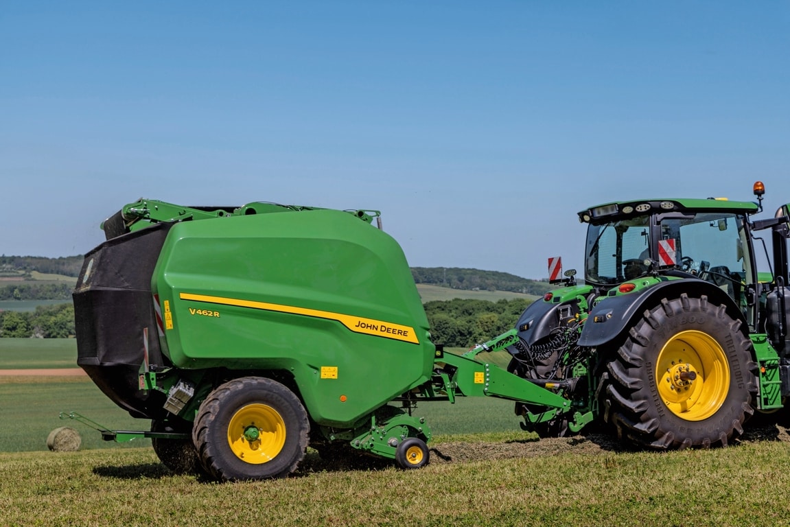 John Deere V462R ťahaný traktorom John Deere 6R 185, ktorý lisuje seno